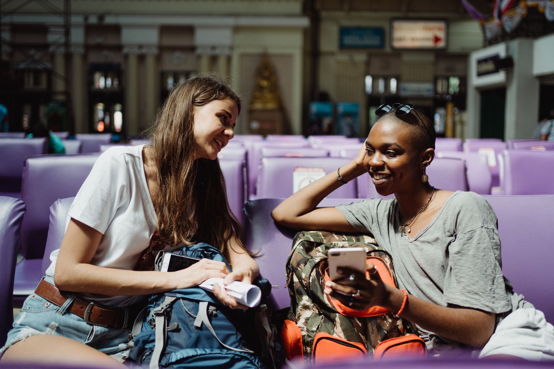 Two passengers laughing together in a station waiting hall